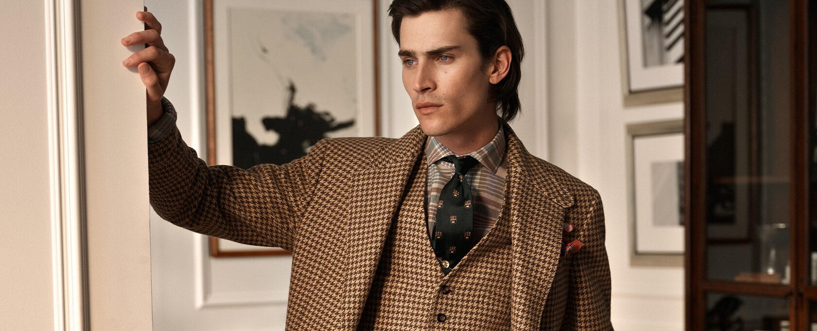 Mężczyzna w eleganckiej, brązowej marynarce i kamizelce w pepitkę, koszula w paseczki, zielony krawat z motywem, poszetka; smart casual na jesień 2025, styl vintage, wnętrze klasyczne