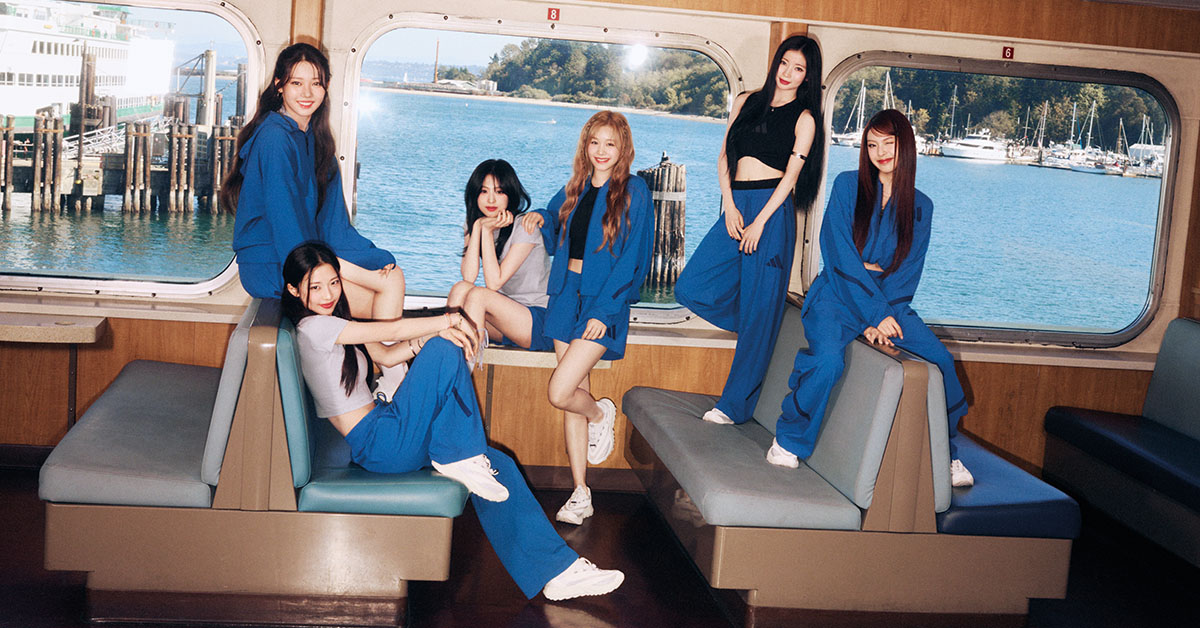 Grupa kobiet w sportowych stylizacjach siedzi we wnętrzu promu na tle portu